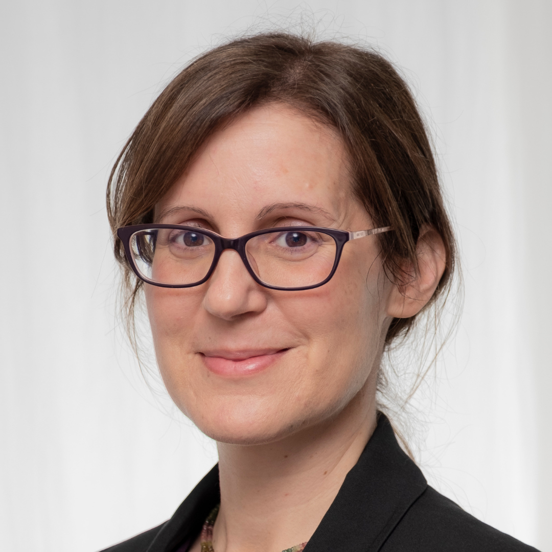 A headshot of Dr. Mika Ahuvia against a gray background